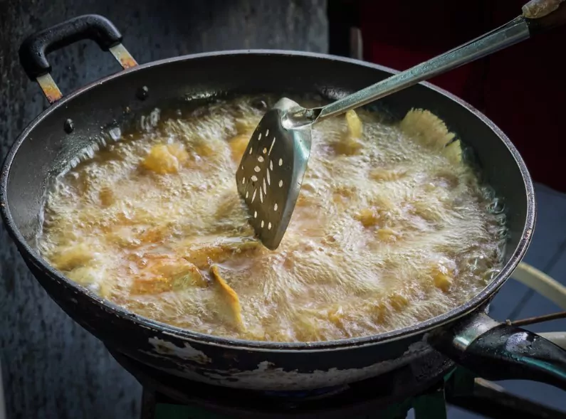 samosas frying inside a deep frying pan