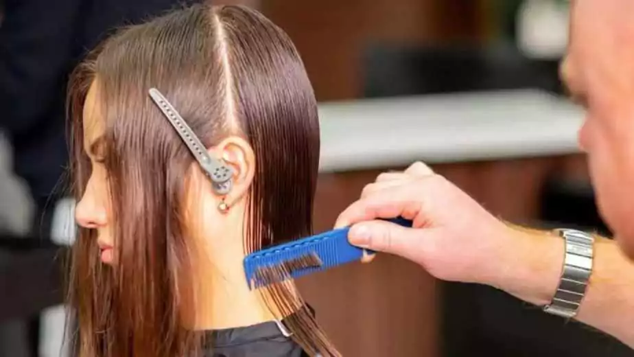 a barber sectioning the hairs of a woman for hair straightening