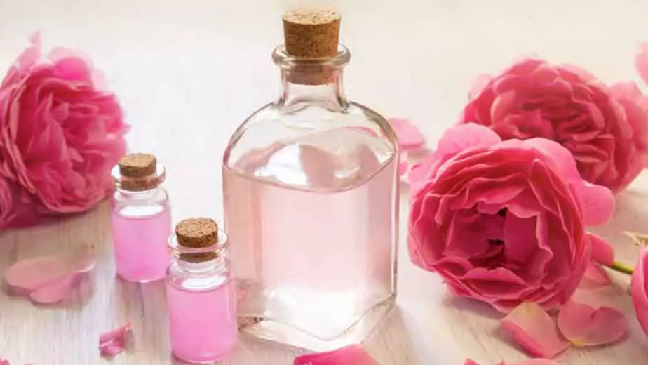a bottle of rose water surrounded by rose petals