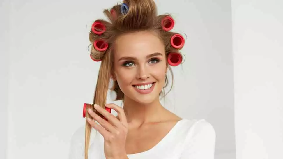 woman applying hair rollers on her hair