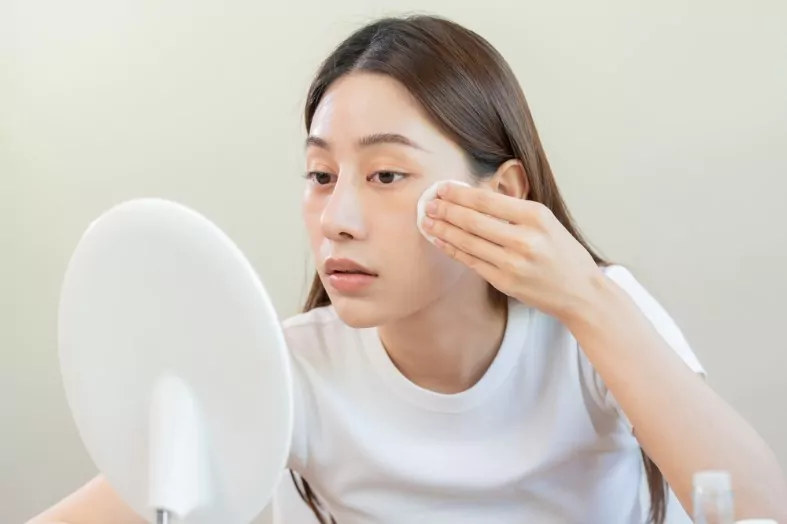 an asian girl applying mild cleanser