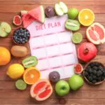 different healthy food with diet plan on wooden table