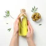 a woman holding a bottle of olive oil in her hands