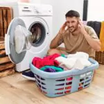 young man covering his ears due to loud noise from washing machine