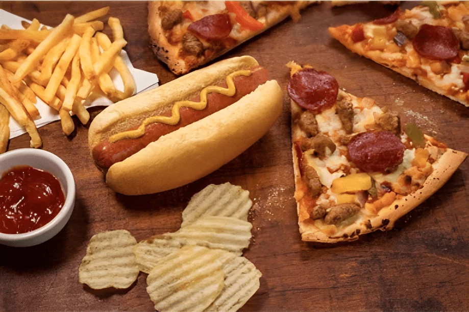 variety of processed foods with pizza hot dog chips and french fries