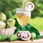 noni fruit or morinda citrifolia with noni juice and leaf in the basket for health on the wooden table background