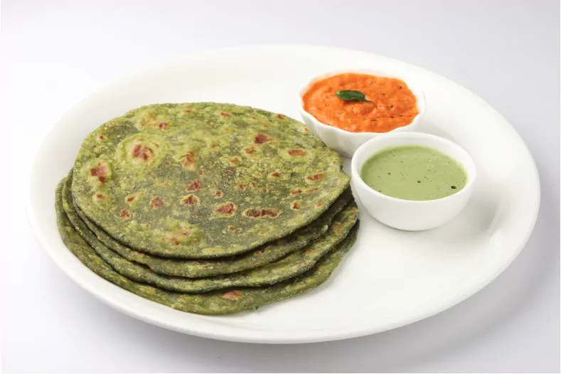 palak paratha or indian flat breads made from spinach served with a mint dip and mango pickle