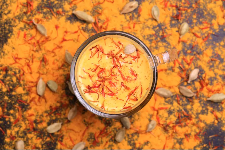 traditional Indian cuisine saffron milk with cinnamon cardamom and turmeric on black slate background