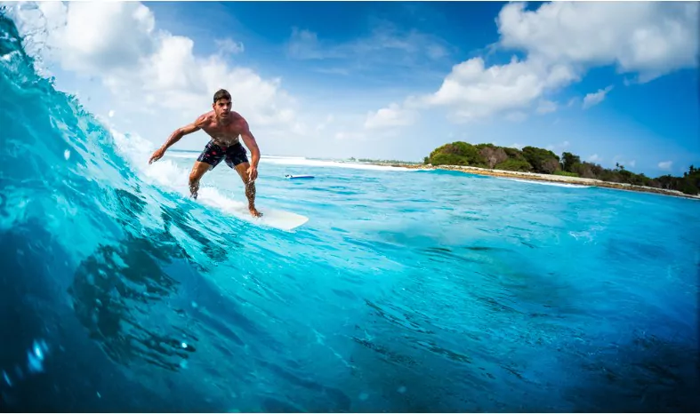 young athletic surfer rides the ocean wave on sultans surf spot in maldives