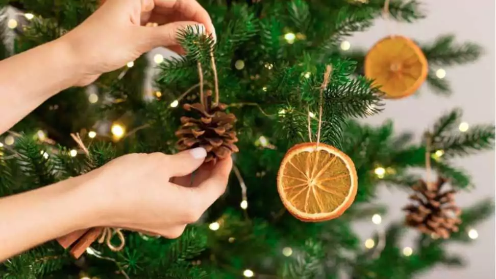 female hands hanging handmade decoration on christmas tree