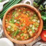 vegetable soup in wooden bowl and ingredients on wooden rustic table