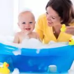 happy baby taking a bath playing with foam bubbles