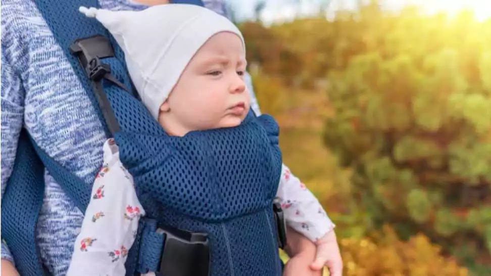 baby girl in a carrier carried by her mother on the body