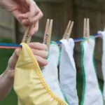 a mom hangs cloth diapers on a clothesline to dry in the sun