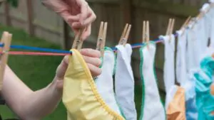a mom hangs cloth diapers on a clothesline to dry in the sun