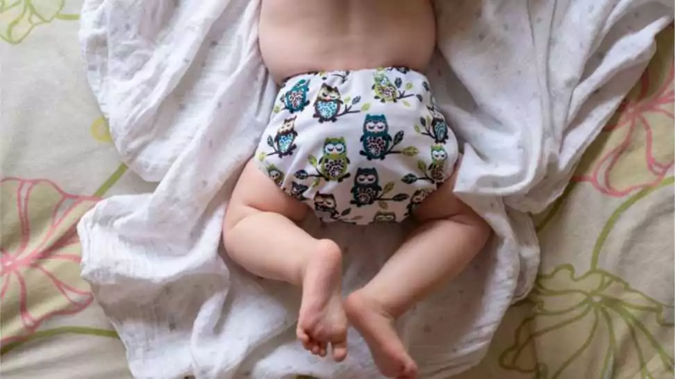 baby wearing a modern reusable cloth diaper with a pretty print