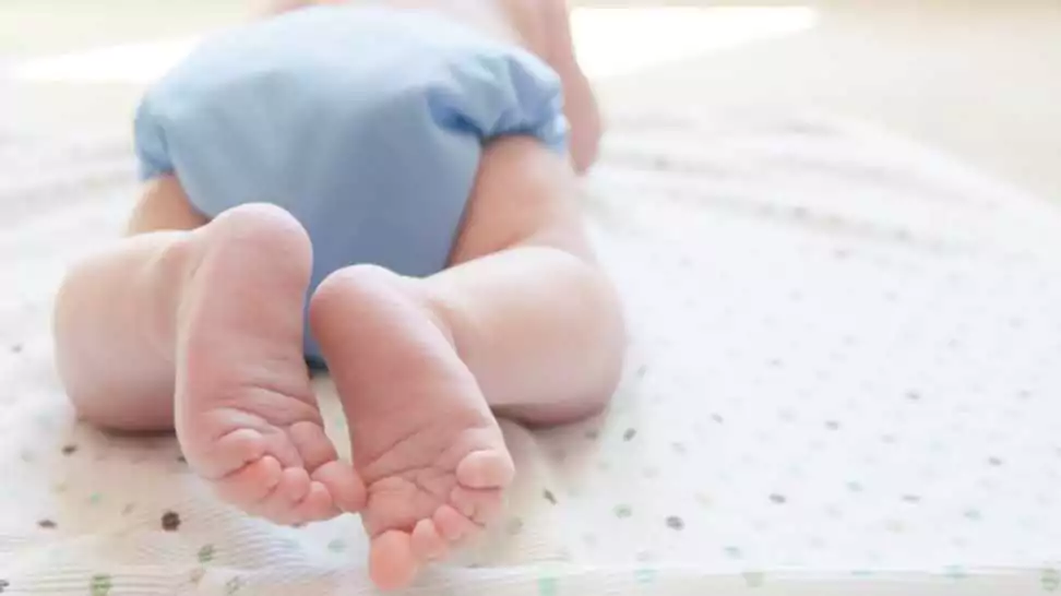 close up of feet and toes of a baby wearing blue cloth diaper
