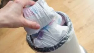 woman hand put used diaper to the trash bin full of used diapers