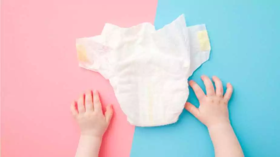 baby hands and white diaper on light pink blue table background