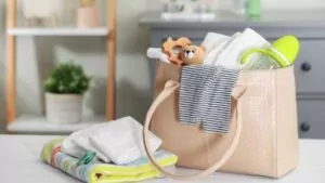 mother's bag with baby's stuff on white wooden table indoors