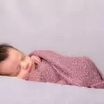 beautiful newborn baby girl swaddled in a knit wrap