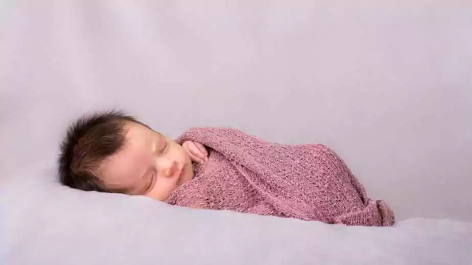 beautiful newborn baby girl swaddled in a knit wrap