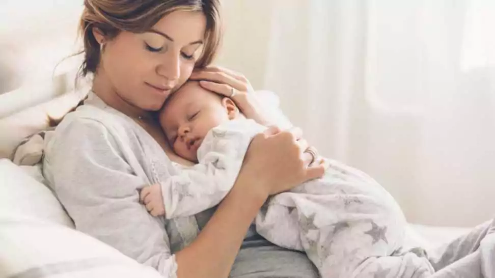 bright portrait of happy mum holding sleeping infant child on hands