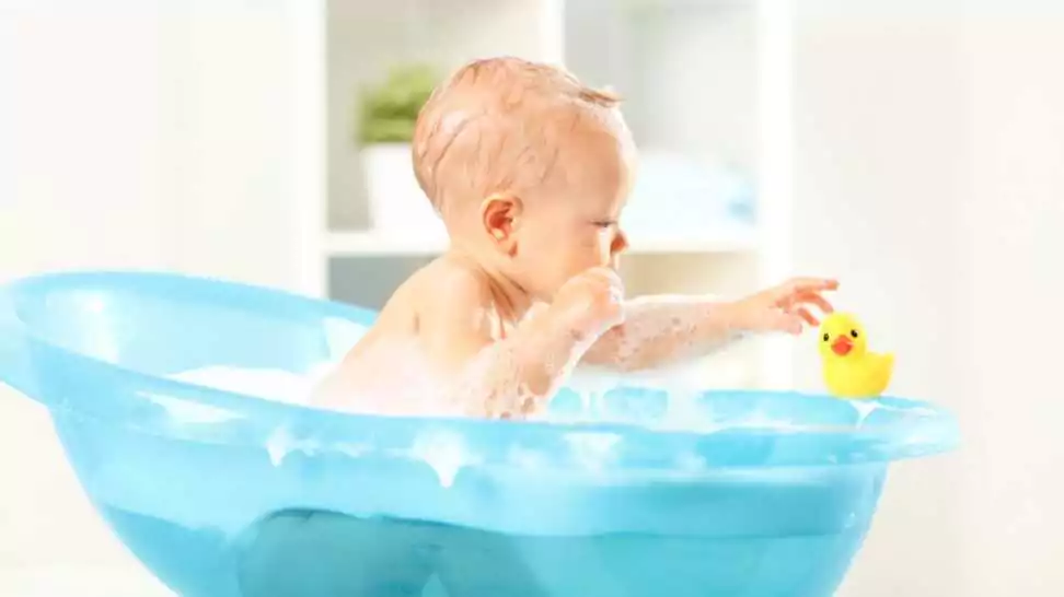 a happy toddler bathing in bathtub