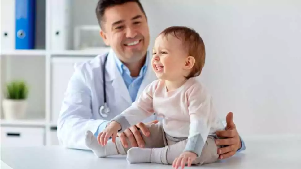 happy doctor or paediatrician holding baby on medical exam at clinic