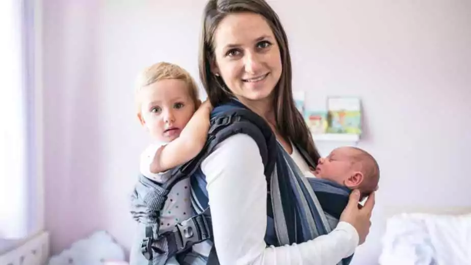 mother with her children in a sling and baby carrier