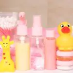 baby accessories and toy on table against bathroom liquid soap package shampoo bottle sponge rubber toy and towel on a white background