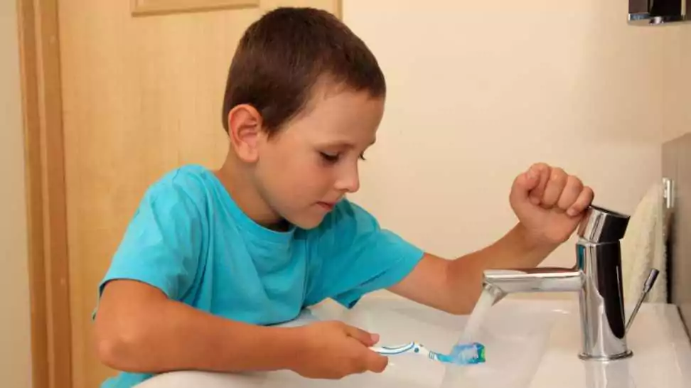 six years old boy cleaning toothbrush