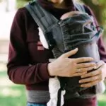 mom hands hug the baby in a sling