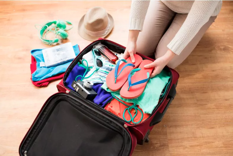close up of woman packing travel bag for vacation