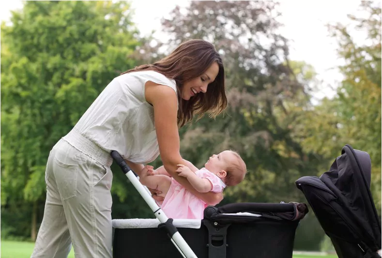 side view portrait of a mother putting baby into a stroller