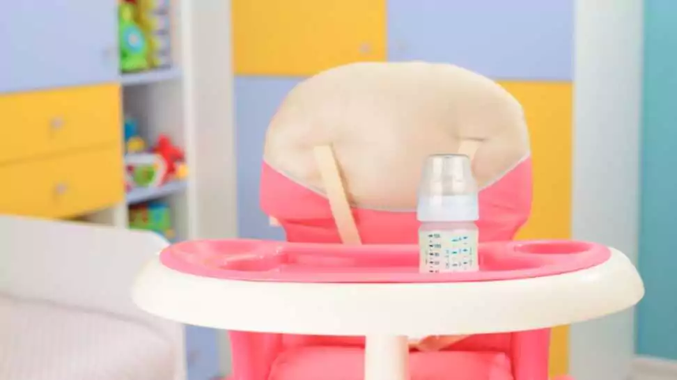 baby pink high chair and bottle with milk in baby room