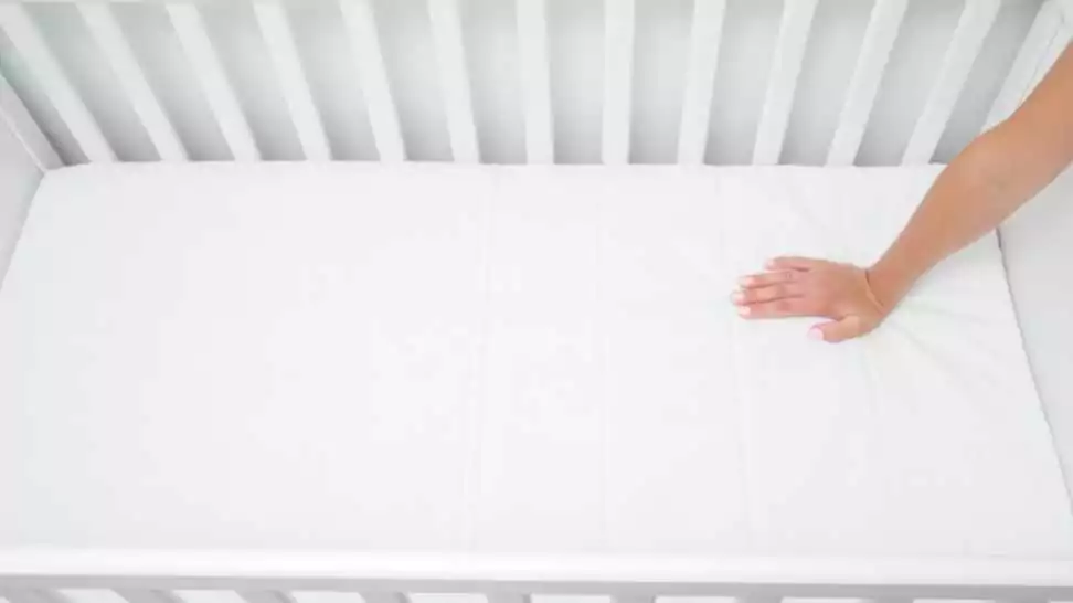 mother checking hardness and softness of baby bed