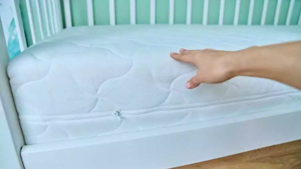 close up of woman's hand checking the size and fit of mattress on children's bed