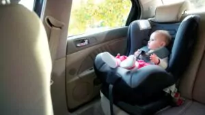 adorable baby girl sitting on an infant car seat and looking outside the window