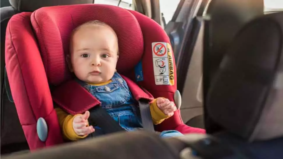 father fasten his little baby in the car seat