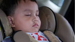 cute little kid sitting and sleeping in a torn infant car chair