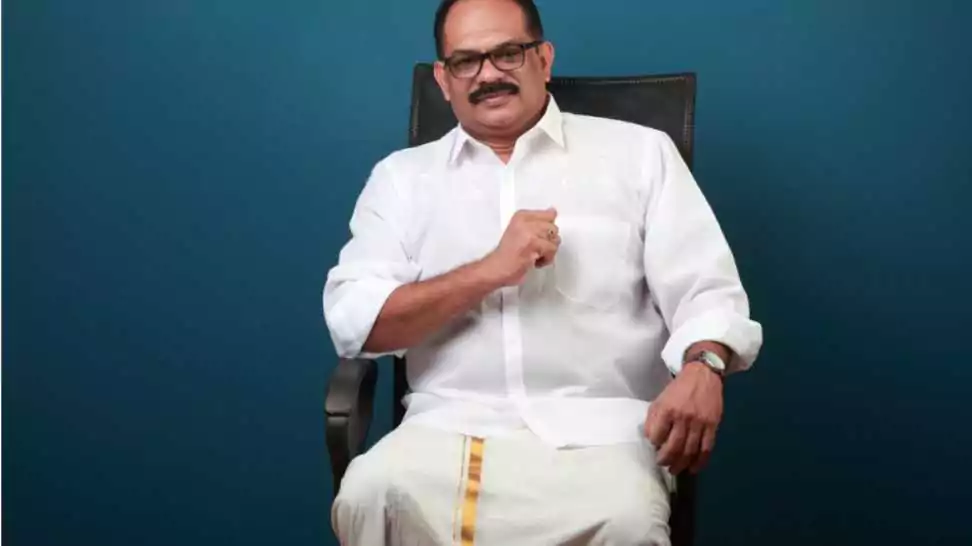 middle aged man wearing kerala style traditional dhoti sitting on a chair