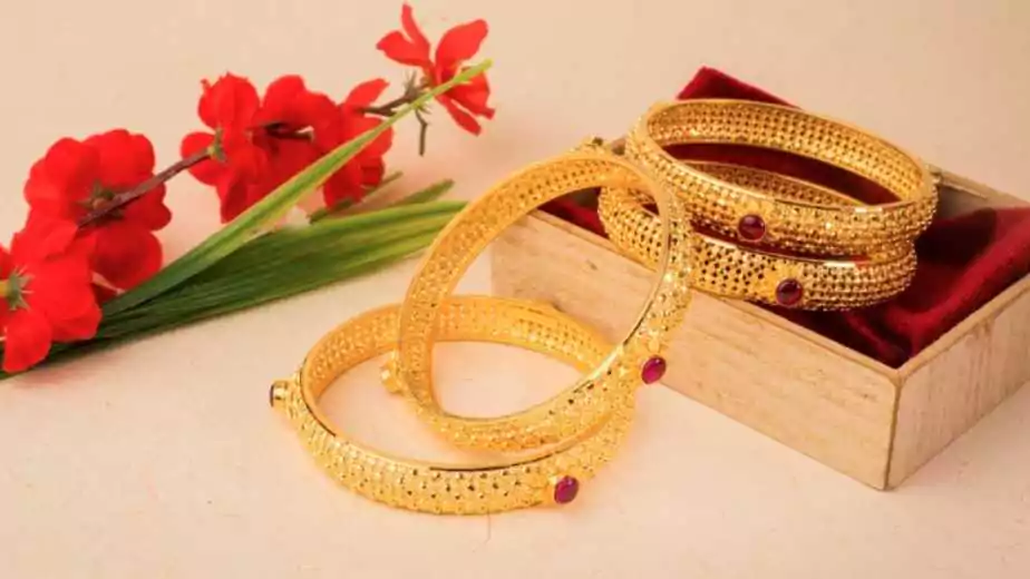 gold indian bangles near a box along with red flowers