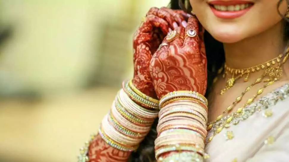 indian bride wearing white dress with beautiful henna on her hands with bangles