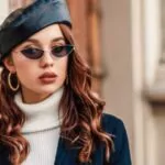 outdoor close up autumn portrait of young elegant fashionable woman wearing trendy leather beret sunglasses hoop earrings blazer turtleneck posing in street of european city