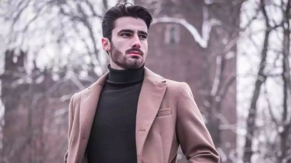 handsome young man standing outside in winter wearing a turtleneck with a blazer