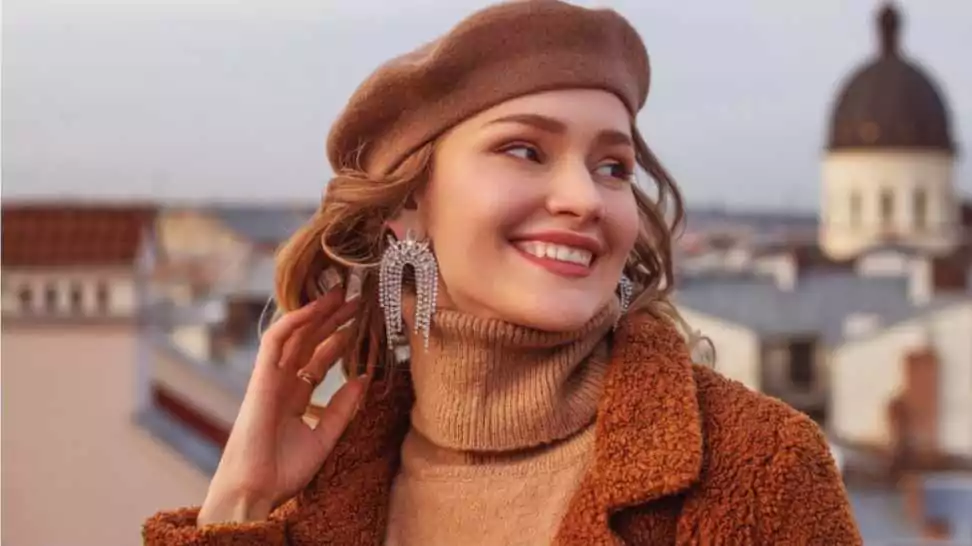 outdoor close up fashion portrait of elegant happy smiling woman wearing beige beret turtleneck brown coat