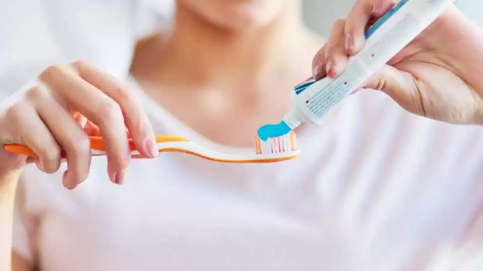 closeup shot of a young woman squeezing toothpaste onto her toothbrush in the bathroom at home