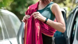 beautiful young mother is preparing a ring sling to take the baby out of the car for a walk