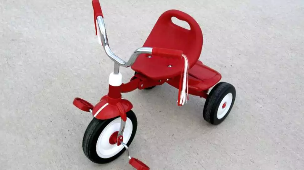 an empty red tricycle on a cement background